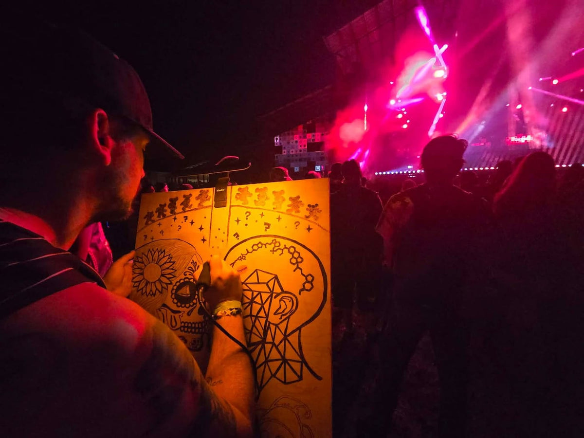 Chandler burning a live piece in front of a festival stage